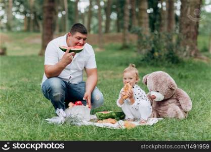 Happy smiling young father and daughter on picnic in park at summer day. The concept of summer holiday. Father&rsquo;s, baby&rsquo;s day. Spending time together. selective focus. Happy smiling young father and daughter on picnic in park at summer day. The concept of summer holiday. Father&rsquo;s, baby&rsquo;s day. Spending time together. selective focus.