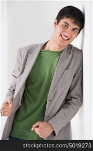 Happy smiling young man leaning against white wall