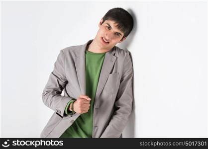 Happy smiling young man leaning against white wall with copy space an the right