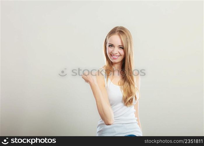 Happy smiling young woman. Girl celebrating success clenching fist on gray