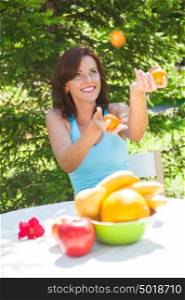 Happy Smiling Young Woman Juggling Oranges at her Garden