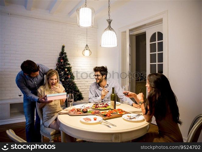 Happy smiling young woman receives gift from young man for New Year or Christmas at home