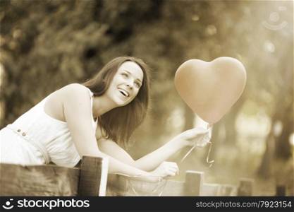 Happy Smiling Young Woman Standing with a Red Shaped Heart Balloon Outdoors