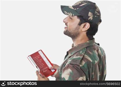 Happy soldier holding greeting card and looking away