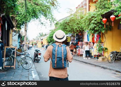 happy Solo traveler sightseeing at Hoi An ancient town in central Vietnam, man traveling with backpack and hat. landmark and popular for tourist attractions. Vietnam and Southeast Asia travel concept