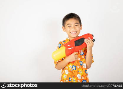 Happy Songkran Day, Asian kid boy with floral shirt hold water gun, Thai child funny hold toy water pistol and smile, isolated on white background, Thailand Songkran festival national culture concept