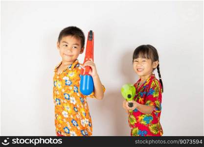 Happy Songkran Day, Asian kid girl and boy holding plastic water gun, Thai child funny smiling hold toy water pistol, isolated on white background, Thailand Songkran festival national culture concept