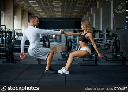 Happy sportive couple doing push-ups, training in gym. Athletic man and woman on workout in sport club, active lifestyle. Sportive couple doing push-ups, training in gym