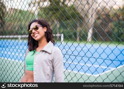 Happy sporty brunette woman near tennis court