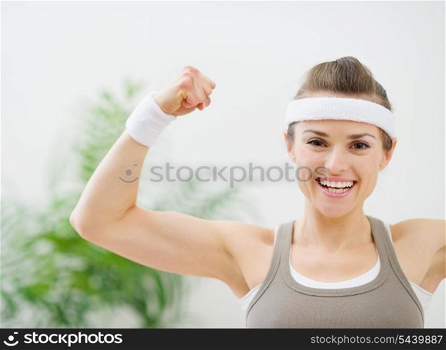 Happy sporty girl showing biceps