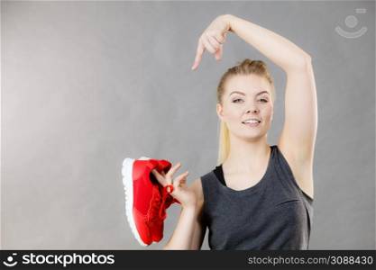 Happy sporty smiling woman presenting sportswear trainers red shoes, comfortable footwear perfect for workout and training.. Happy woman presenting sportswear trainers shoes