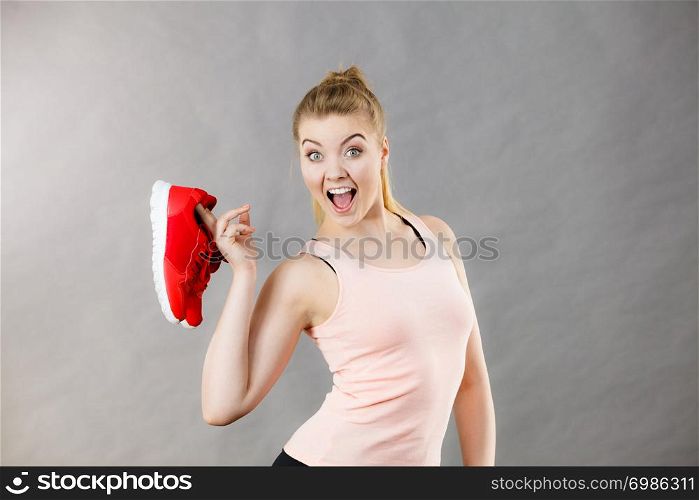 Happy sporty smiling woman presenting sportswear trainers red shoes, comfortable footwear perfect for workout and training.. Happy woman presenting sportswear trainers shoes