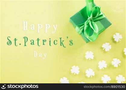 Happy St Patrick&rsquo;s Day decoration background concept. Top view gift box green clover leaves, shamrocks leaves holiday symbol with copy space on pastel yellow background