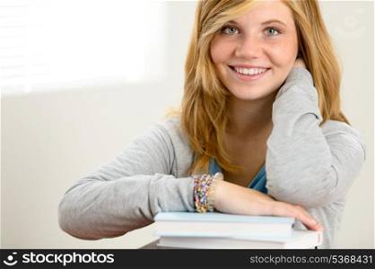 Happy student girl leaning over pile of books