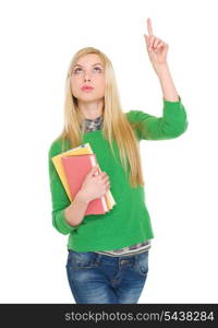 Happy student girl with books pointing up on copy space