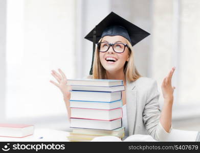 happy student in graduation cap with stack of books