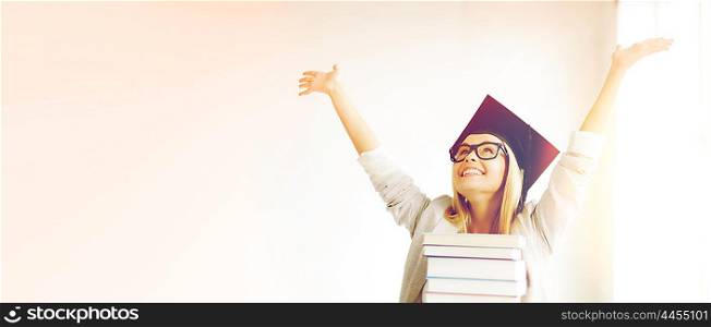 happy student in graduation cap with stack of books. happy student in graduation cap