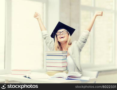 happy student in graduation cap with stack of books. happy student in graduation cap