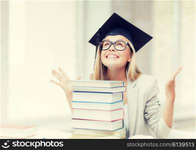 happy student in graduation cap with stack of books. happy student in graduation cap