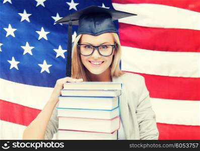 happy student in graduation cap with stack of books over american flag. student in graduation cap