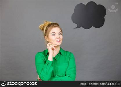 Happy student looking woman wearing green shirt holding black thinking bubble nest to her. Happy woman holding black thinking bubble