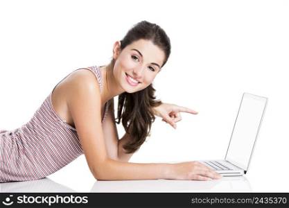 Happy student lying in the floor working and pointing to a laptop, isolated over a white background