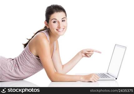 Happy student lying in the floor working and pointing to a laptop, isolated over a white background