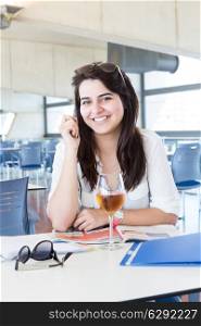 Happy student preparing her exams or simply relaxing at a bar