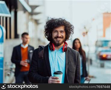 Happy student with afro haircut walking on campus while wearing his manbag and his headphones.. Happy young American holding a coffee. With headphones. Student boy.