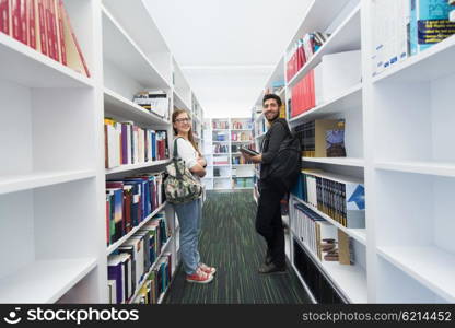 happy students group in school library selecting books to read and walking