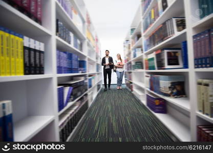 happy students group in school library selecting books to read and walking