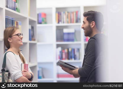 happy students group in school library selecting books to read and walking