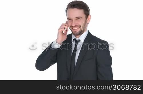 Happy stylish businessman chatting on his mobile phone standing smiling broadly as he looks at the camera, isolated on white