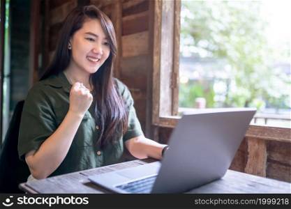 Happy successful business of asian freelance people business female expressed confidence embolden working with laptop computer sitting with coffee cup beside the window of a wooden house background