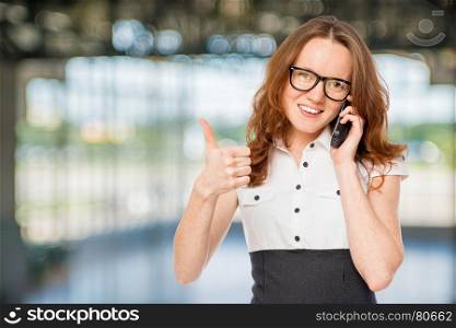 Happy successful businesswoman with phone posing in the office