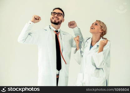 Happy successful doctor celebrates victory in hospital office with another doctor standing beside her for the success of patient treatment.
