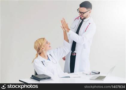 Happy successful doctor celebrates victory in hospital office with another doctor standing beside her for the success of patient treatment.. Happy doctor celebrates success with partner.