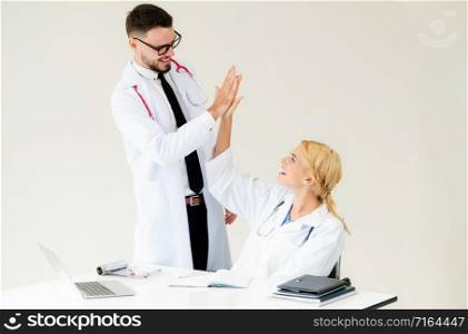 Happy successful doctor celebrates victory in hospital office with another doctor standing beside her for the success of patient treatment.. Happy doctor celebrates success with partner.