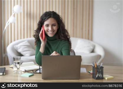 Happy successful Italian business woman having pleasant cellphone conversation while working on laptop at home office, smiling female employee discussing project with copartner by phone at work. Happy Italian businesswoman having pleasant cellphone conversation while working on laptop at home