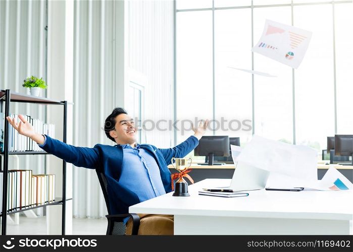 Happy successful of Asian young businessman for threw up the business plan in document paper into the air, laptop computer on table background in office,concept of emotional satisfied with the work