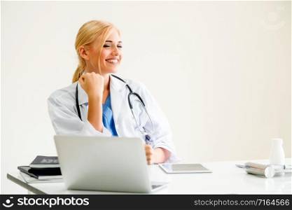 Happy successful woman doctor feels delightful in hospital or healthcare institute while working on medical report at office table. Success concept.. Happy doctor in hospital. Medical success concept.