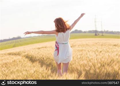 happy summer and freedom. Beautiful girl run at the wheat field on a sunny day