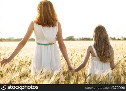 happy summer and vacation. Family - mother with her daughter holding hands in a wheat field 