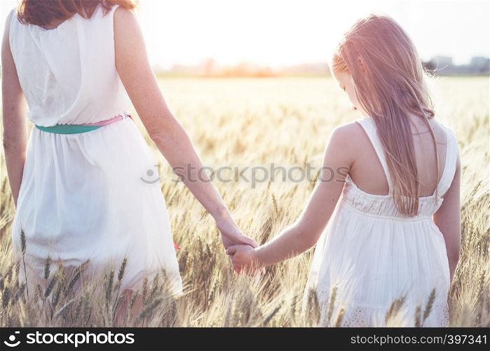 happy summer and vacation. Family - mother with her daughter holding hands in a wheat field