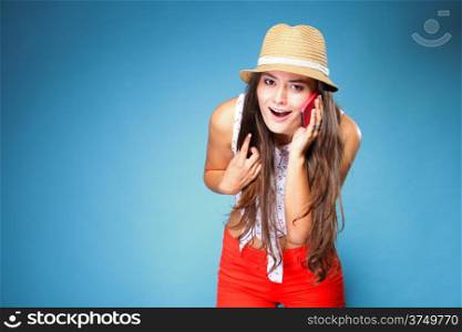 Happy summer girl teenager woman has reaction of surprise as she talking on mobile phone blue background