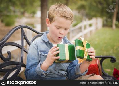 Happy Surprised Young Boy Opens Christmas Gift Outside.