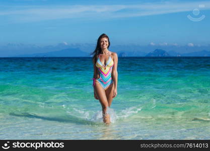 Happy tanned girl in bikini at seaside, blue sea water on background. Girl in bikini at seaside