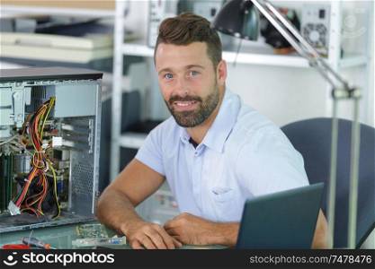 happy technician working on broken computer in his office