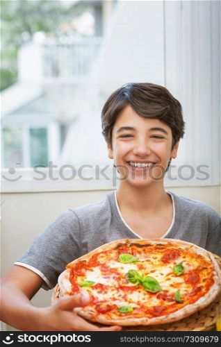 Happy teen boy cooked pizza, cheerful smiling teenager holding homemade pizza, enjoying traditional tasty italian food