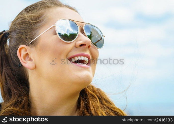 Happy teen woman enjoying her leisure time. Female having long brown hair posing with sky in background. Happy teen woman against clouds